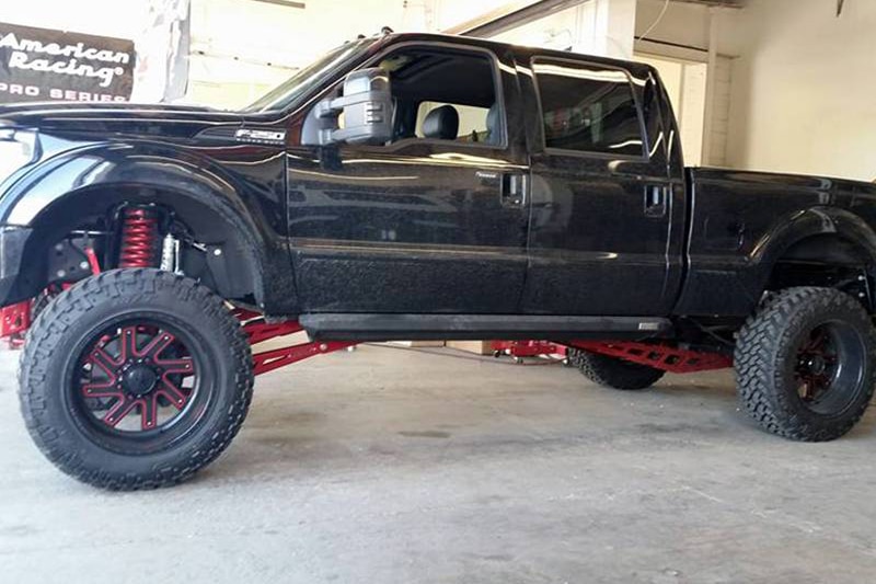 Red and black rims on lifted black truck